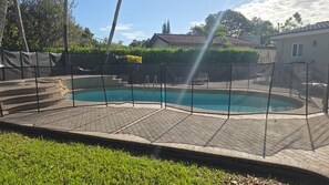A swimming pool with a fenced deck area, surrounded by a hedge and a house in the background. - Miami Home - Private Pool  - We Host (Miami)