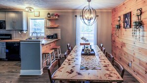 Una cucina moderna con un tavolo da pranzo in legno, elettrodomestici integrati e un lampadario.