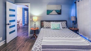 Una camera da letto con un letto, due comodini, una lampada a parete e un quadro.