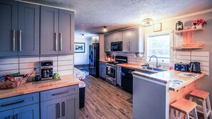 Una cucina moderna con mobili grigi, un piano di lavoro in legno e una penisola centrale con sgabelli.