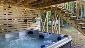 Un bain à remous doté d’une terrasse en bois et d’un escalier en bois menant à l’extérieur.