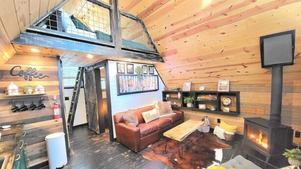 Un intérieur de chalet chaleureux avec une chambre en mezzanine, une cheminée et un coin café.