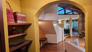A spacious living area with wooden floors, a white sofa, and a staircase leading to an upper level. - Casa Las Colinas by Vilvey Turismo (Chacras de Coria)