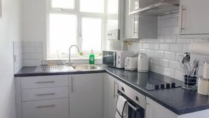 Eine moderne Küche mit weißen Schränken, einer schwarzen Arbeitsplatte und einem Fenster für natürliches Licht.