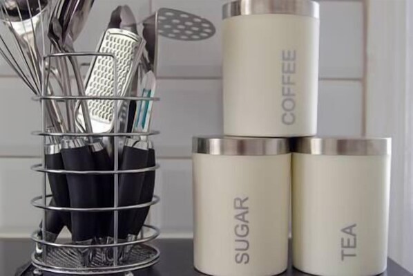 A kitchen counter with a utensil holder and three containers labeled 'SUGAR,' 'COFFEE,' and 'TEA.' - Vibrant 4-Bedroom House With Parking & Garden (Southampton)