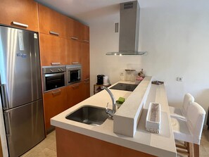 Enjoy cooking in this well-equipped kitchen with a refrigerator, oven, microwave, and island with a sink.
