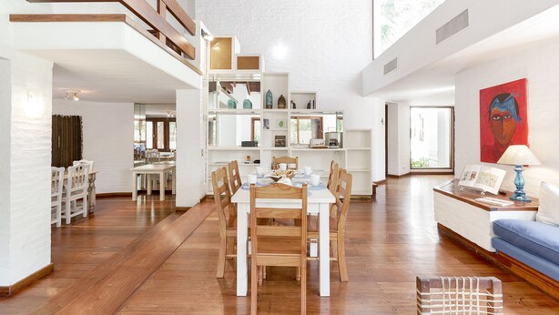 A spacious living area with a dining table, wooden chairs, a sofa, and a bookshelf. - Posada del huerto by Vilvey Turismo (Chacras de Coria)