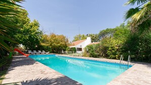 A swimming pool with a slide, surrounded by trees and a building with a red roof. - Posada del huerto by Vilvey Turismo (Chacras de Coria)