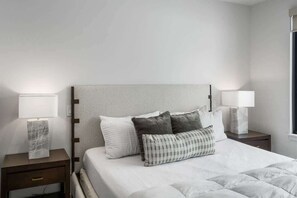A neatly arranged hotel room with a large bed, two bedside tables, and a window.
