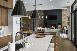 Cozinha moderna com ilha central, iluminação pendente e parede decorativa em pedra.
