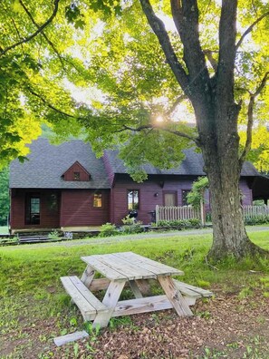 A rustic cabin with a wooden deck and a picnic table in front.