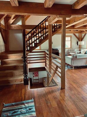 A wooden staircase in a loft-style room with a sofa and a lamp.
