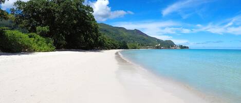 En la playa, arena blanca, sillas reclinables de playa, toallas de playa