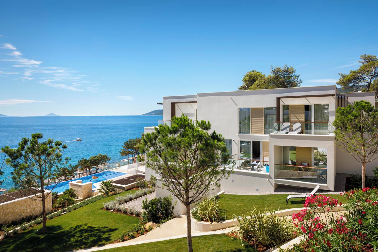 Ein modernes, zweistöckiges Gebäude mit Pool und Meerblick.