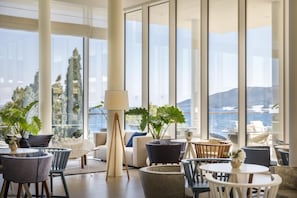 A spacious lounge area with large windows, modern furniture, and potted plants. - Girandella Resort Valamar Collection - Family Hotel (Labin)