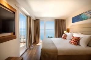 A hotel room with a large bed, a TV, a painting, and a view of the sea. - Girandella Resort Valamar Collection - Family Hotel (Labin)