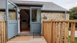 A stone building with a wooden deck and a blue door. - Carines Barns - Pol (Newquay)