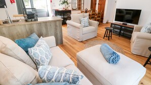 A modern living room with a sofa set, a dining area, and a TV. - Carines Barns - Pol (Newquay)