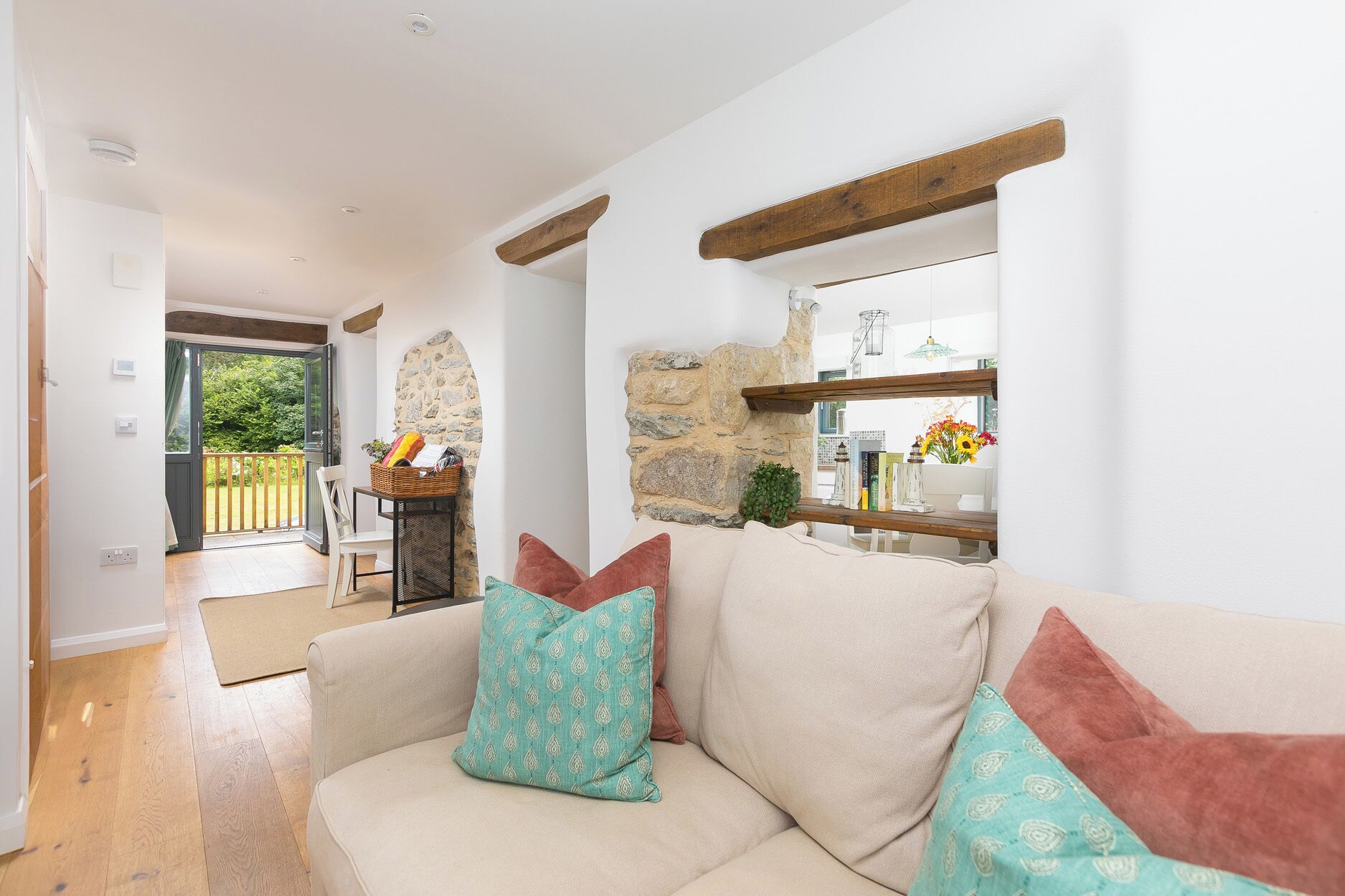 A cozy living room with a sofa, a stone wall, and a wooden beam ceiling.