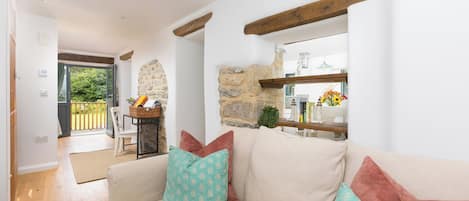 A cozy living room with a sofa, a stone wall, and a wooden beam ceiling.