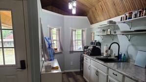 A kitchen with white cabinets, a countertop, a coffee maker, and a sink. - Newly transformed farm cottage off the beaten path! (Minford)