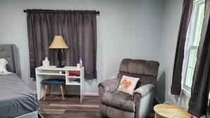 A bedroom with a bed, a desk, a chair, and a small round table. - Newly transformed farm cottage off the beaten path! (Minford)