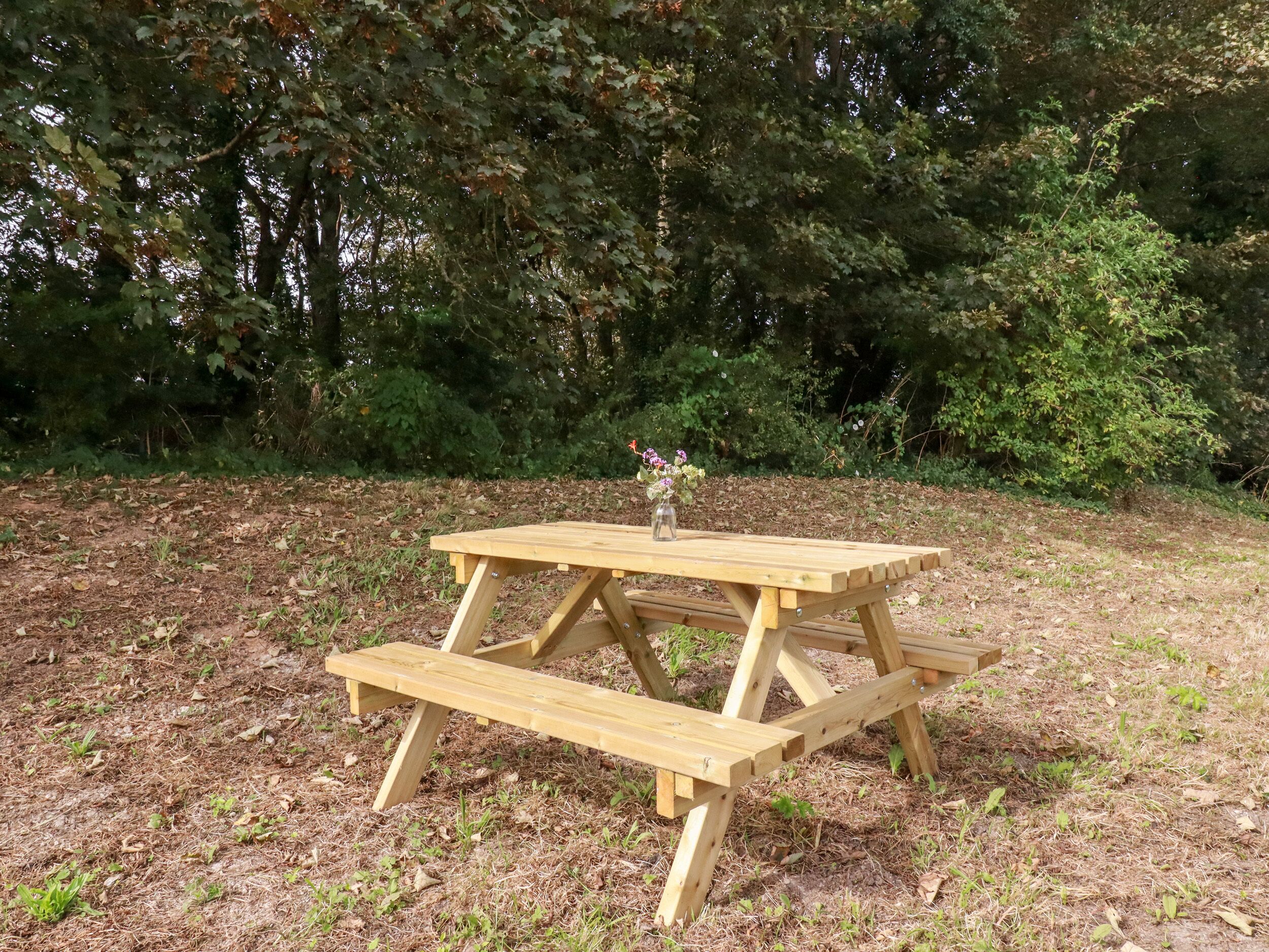 Un tavolo da picnic in legno con panche, immerso nel verde.
