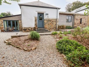 A two-story house with a stone exterior and a blue door. - Carines Barns - Wesley Barn (Newquay)