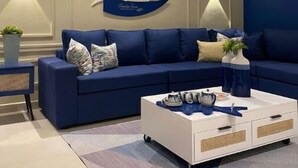 Un saló modern amb un sofà blau, una taula de cafè blanca i aplics decoratius de paret.
