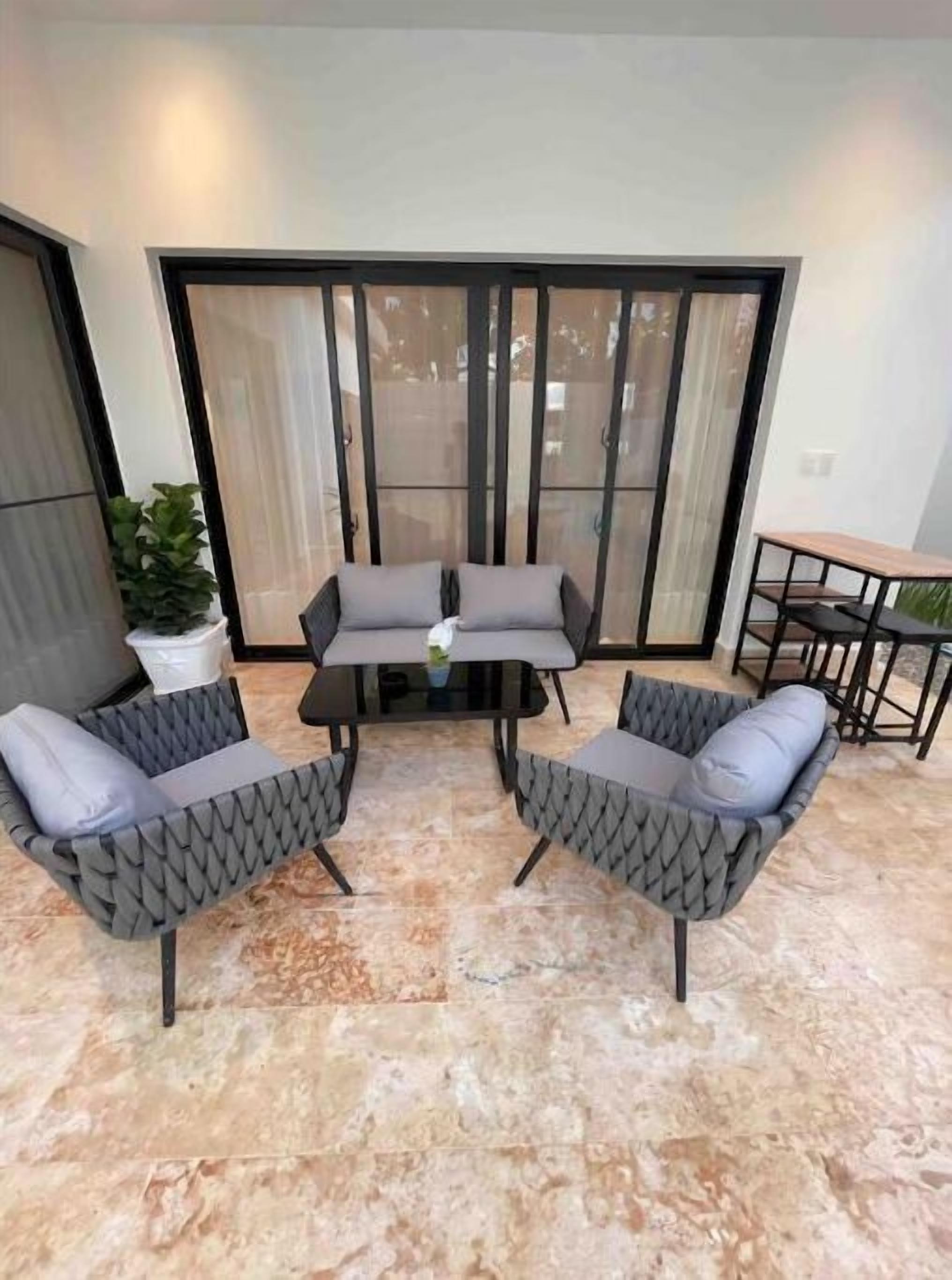 A patio area with a table and two chairs, a potted plant, and a sliding glass door.