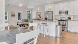 Une cuisine moderne avec des meubles blancs, des appareils en acier inoxydable et un îlot central doté de tabourets.
