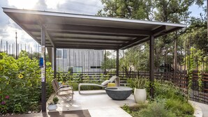 A covered outdoor patio with a modern seating area, including a lounge chair and a round table. - Kasita Nest is a prefabricated, smart home for romantic getaways. (Austin)