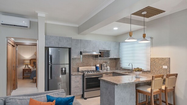 Una cocina moderna con encimeras de granito, electrodomésticos de acero inoxidable y una isla central con taburetes de bar.