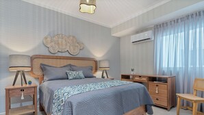Un dormitorio con cama, mesitas de noche, cómoda y una silla.