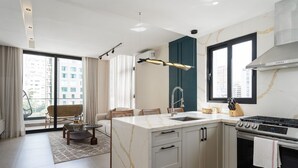 Une cuisine moderne dotée d’un grand îlot central, d’un four encastré et d’un coin repas avec un canapé et des chaises.
