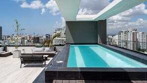 Une piscine sur le toit offrant une vue sur la ville, des espaces de détente en plein air et une architecture moderne.