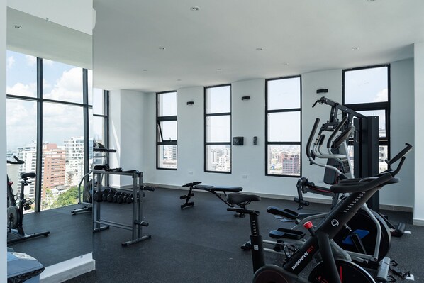 A gym with large windows, exercise equipment, and a view of the city.