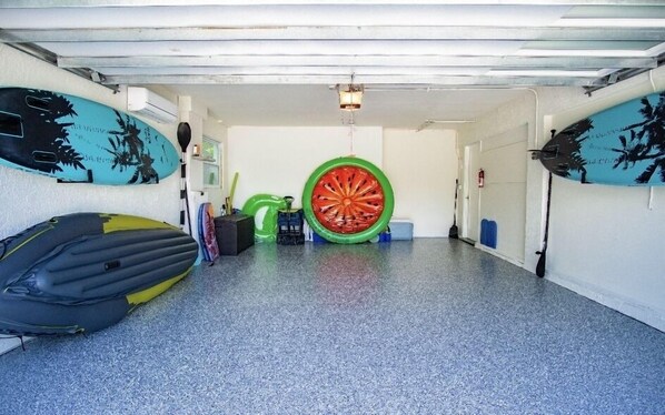 Een garage met een grote opblaasbare band in het midden, een kajak en een surfboard tegen de muur.