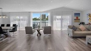 Amplia sala de estar con una mesa de comedor, sillas, un sofá y un balcón con vistas a edificios.