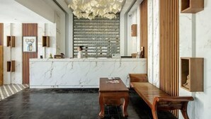 A modern interior with a marble reception desk, wooden accents, and a patterned ceiling.