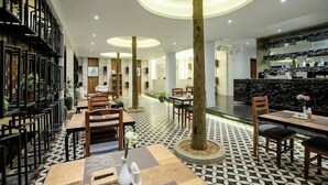 A modern hotel lobby with a central column, patterned floor, and seating areas.