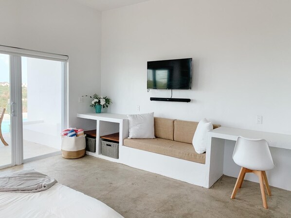 A modern bedroom with a bed, a sofa, a TV, and a view of the outdoors.