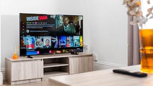 En platt-TV placerad på ett trästativ, med Netflix-gränssnittet synligt och där serien ”Inside Man” samt andra filmer visas.