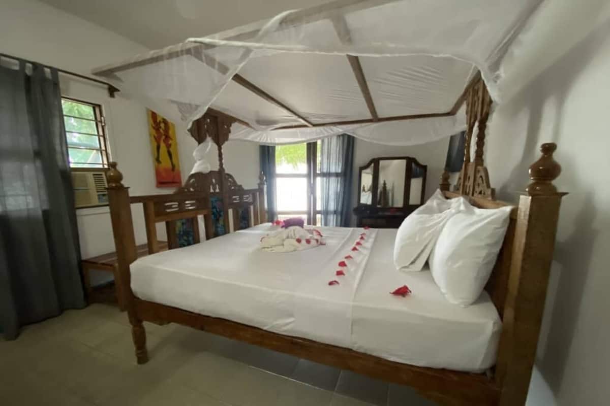A wooden bed with a canopy, a bedside table, and a mirror.