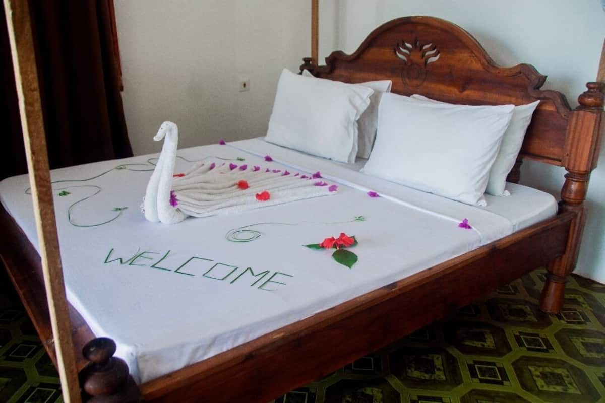 A bed with a 'WELCOME' sign, white pillows, and a swan decoration.