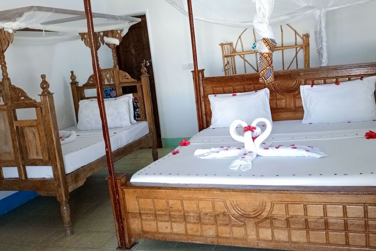 A traditional wooden bed with a canopy, a wooden chair, and a small table.