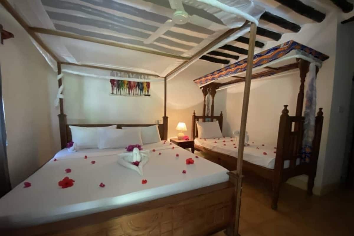 A room with two wooden beds, each with a canopy, and a wall-mounted artwork.