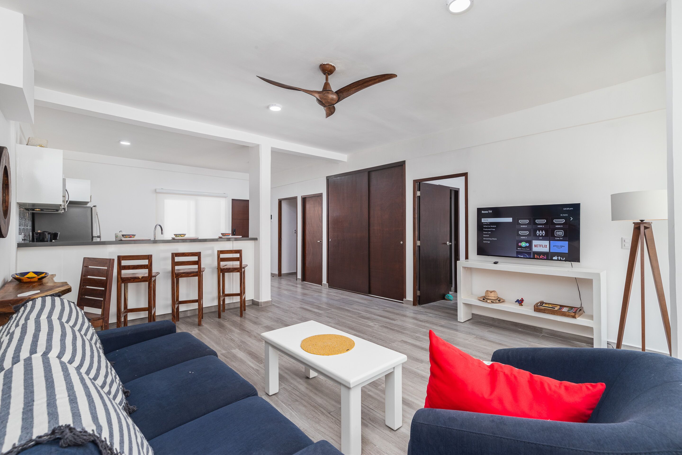 A modern living room with a sofa, a coffee table, a TV, and a ceiling fan.
