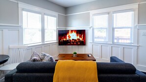 A living room with a fireplace, a TV mounted above it, and a cozy seating area with a sofa and a small table. - Desirable Studio Park Views W/D (San Diego)