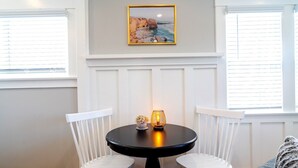 A round table with two white chairs, a candle, and a framed picture on the wall. - Desirable Studio Park Views W/D (San Diego)